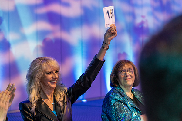 An attendee raises her bidder number to make a donation.